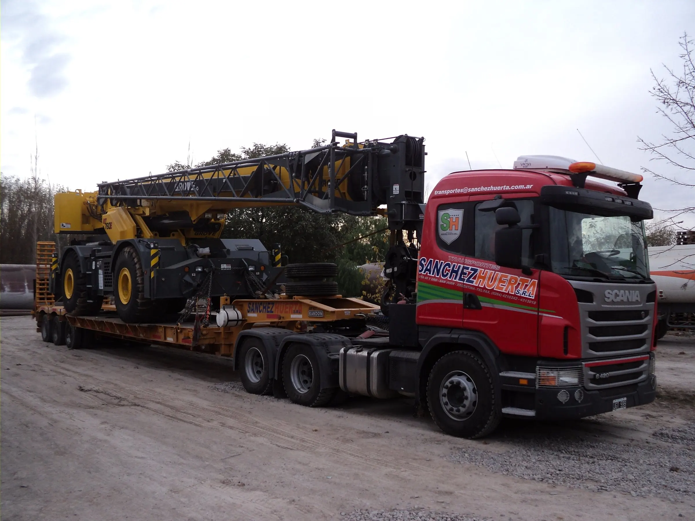 Tractor Scania de Transporte Sanchez Huerta remolcando un carretón de baja cama con una grúa autopropulsada amarilla desarmada