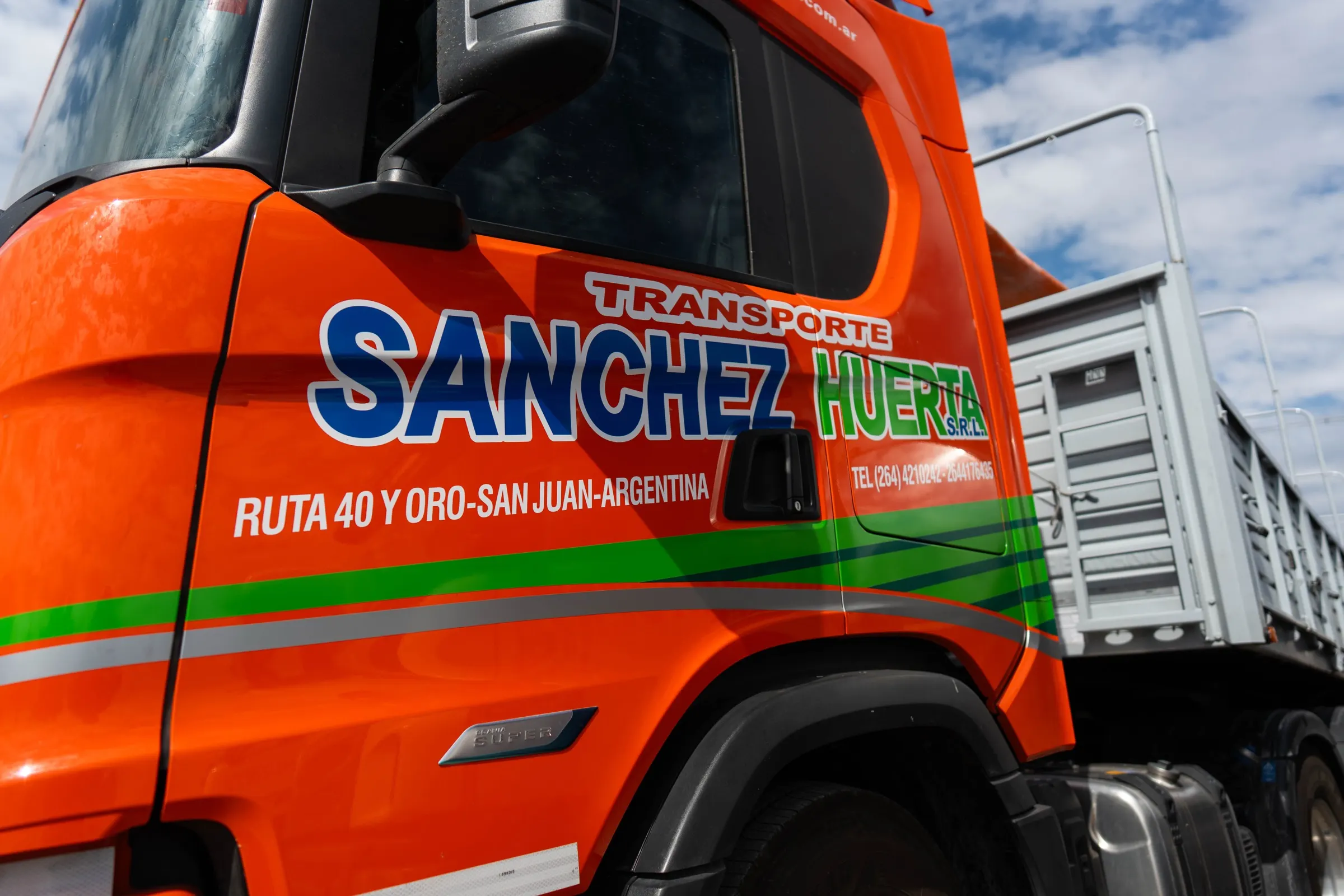 Detalle de la cabina de un camión Scania de Transporte Sanchez Huerta, con el logo de la empresa y la dirección Ruta 40 y Oro, San Juan, Argentina, pintados en la puerta