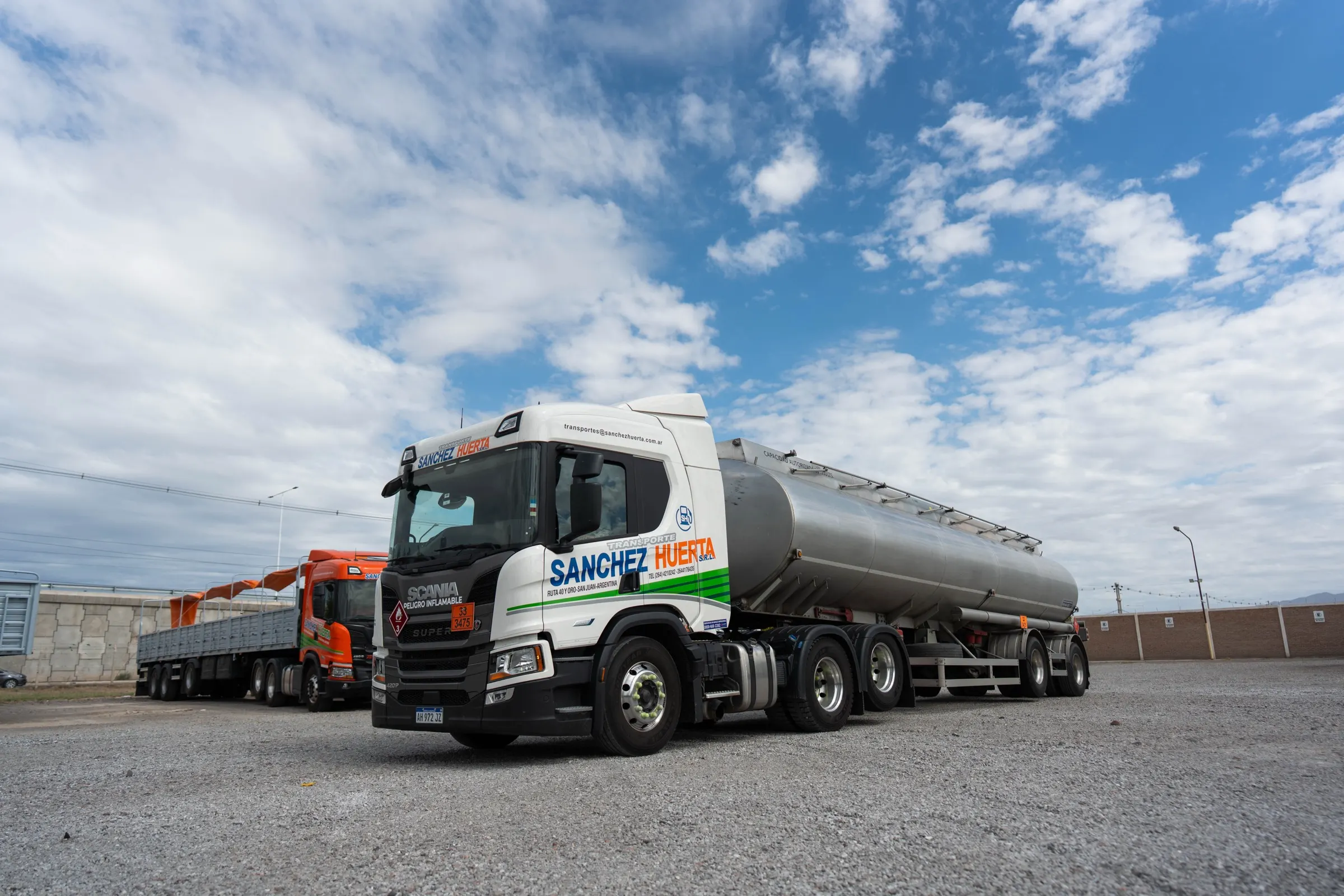 Semirremolque cisterna para transporte de combustibles con el rombo de "Peligro Inflamable" en la cabina, estacionado junto a un semirremolque de carga general